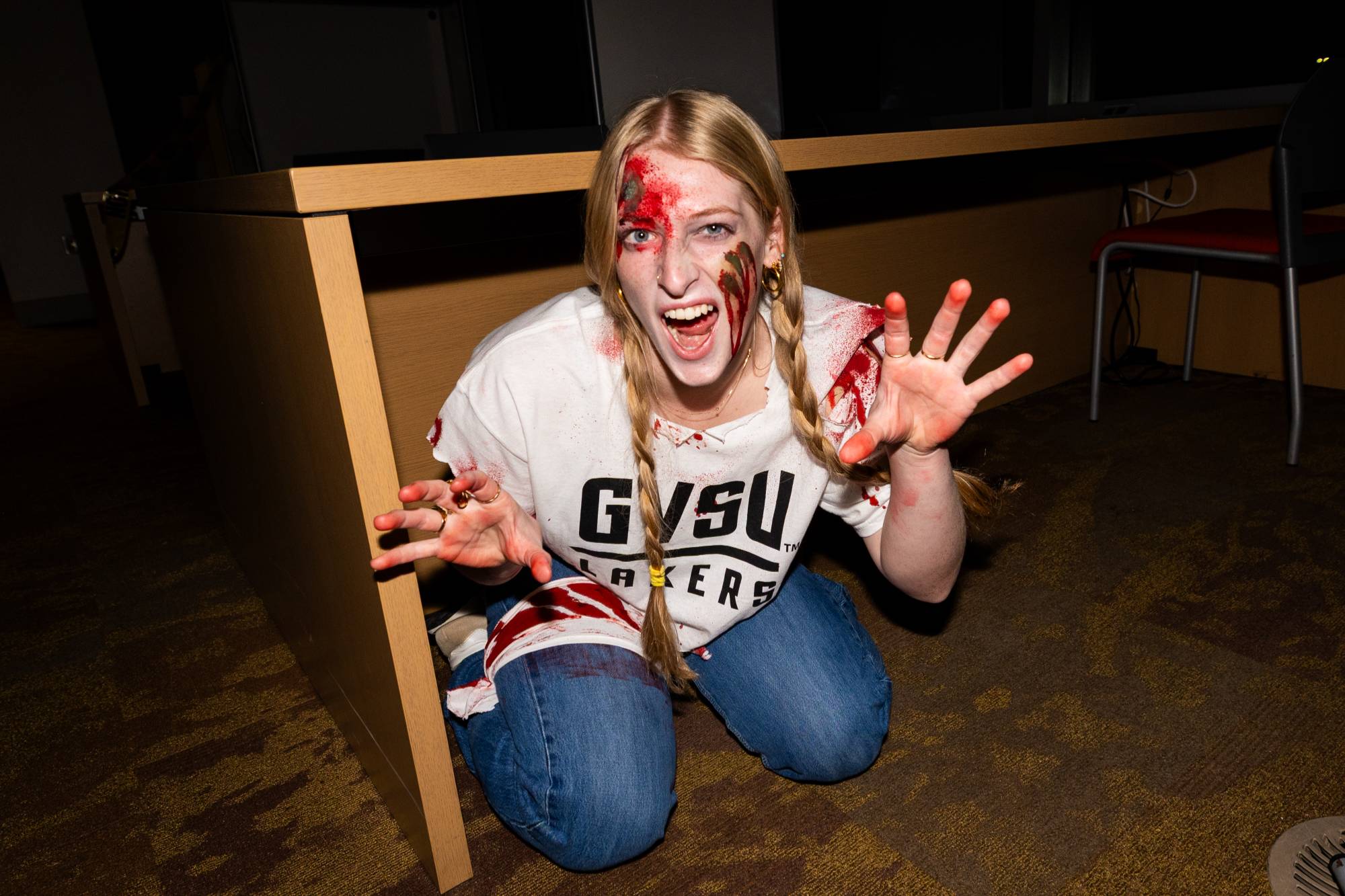 girl dressed up as zombie crouching under table